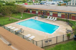 A rectangular pool with a surrounding fence, lounge chairs, and a building in the background. - Rodeway Inn Georgetown (Georgetown)
