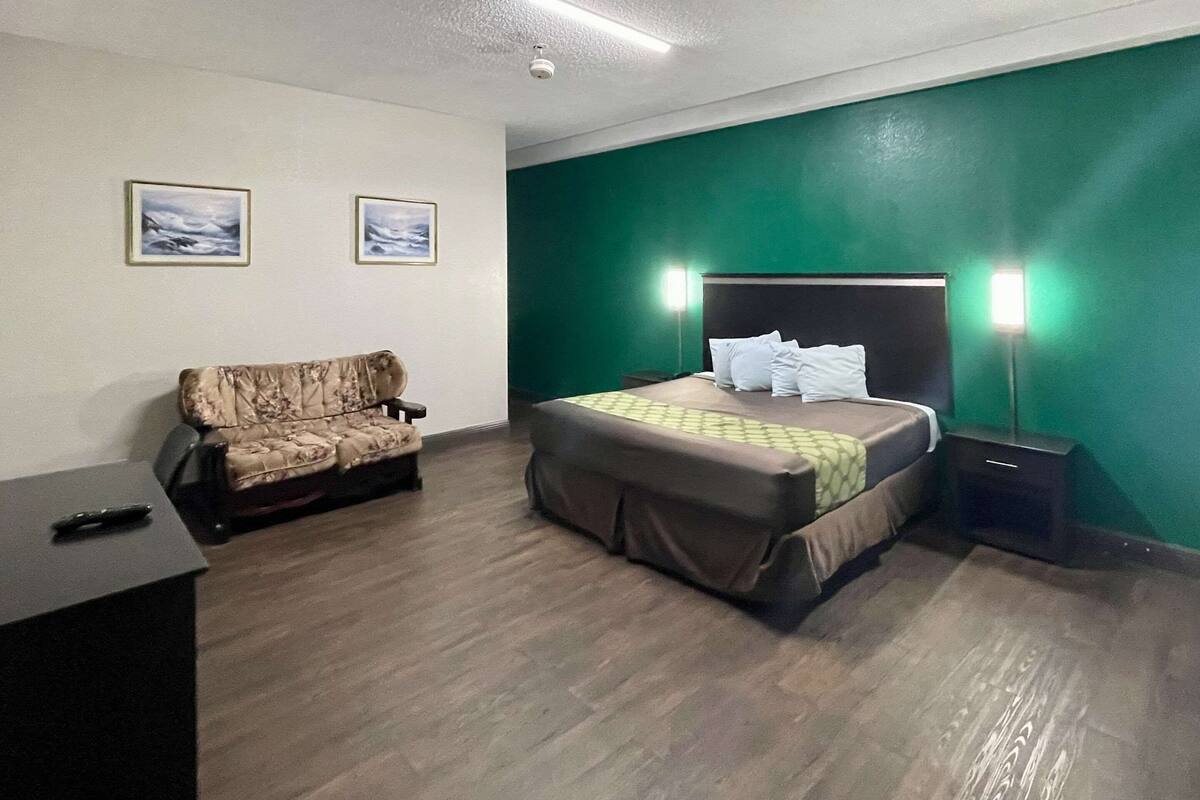 Ein Hotelzimmer mit einem Bett, einer Couch, einem Schreibtisch und zwei Wandleuchten.