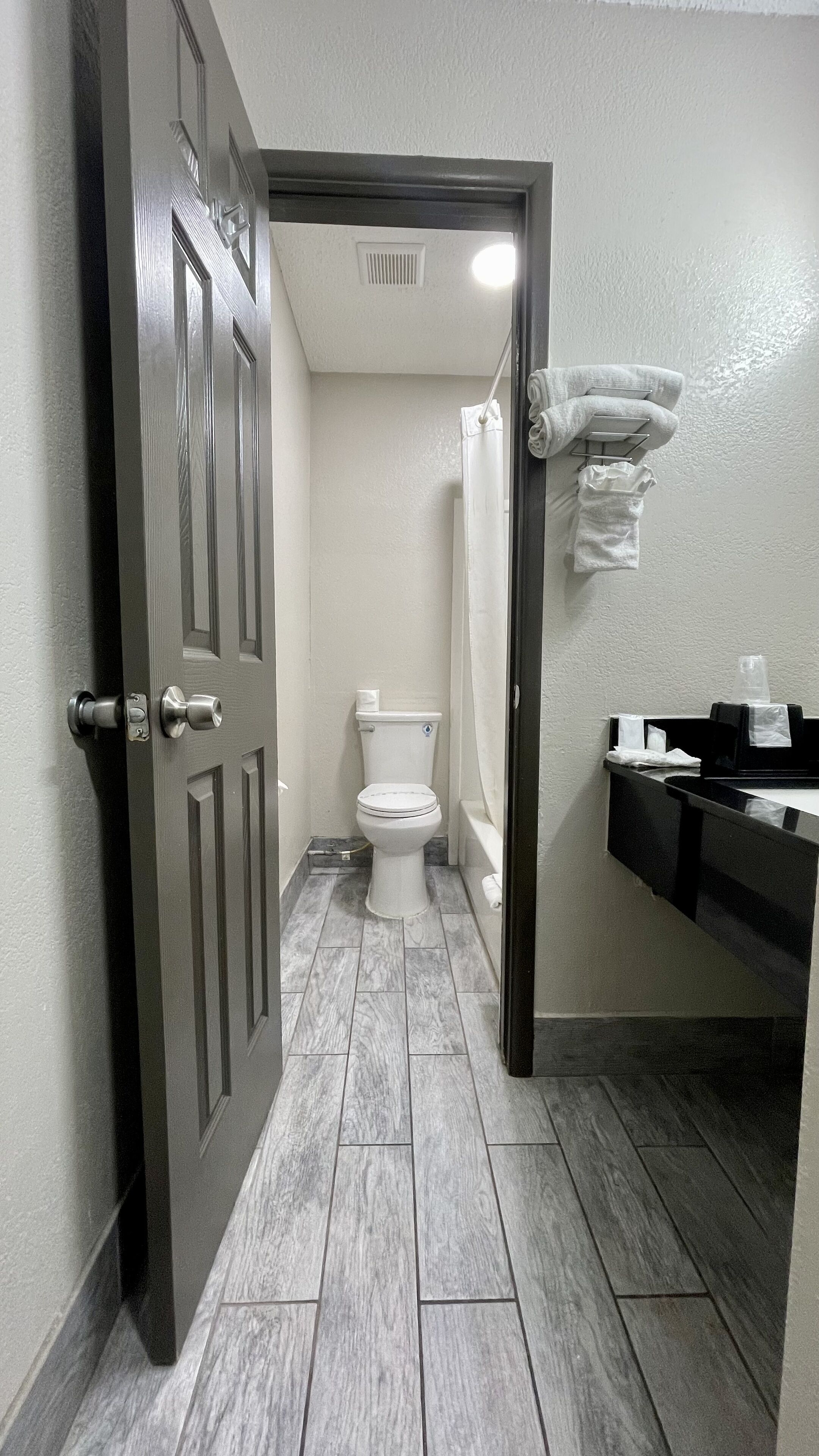 A bathroom with a toilet, shower, and a towel rack.