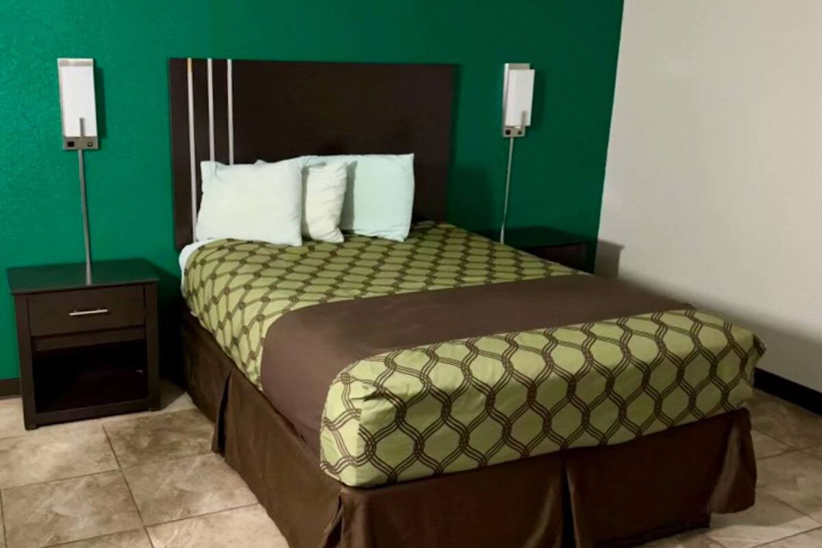 Ein Hotelzimmer mit einem Bett, zwei Nachttischen und grünen Wänden.