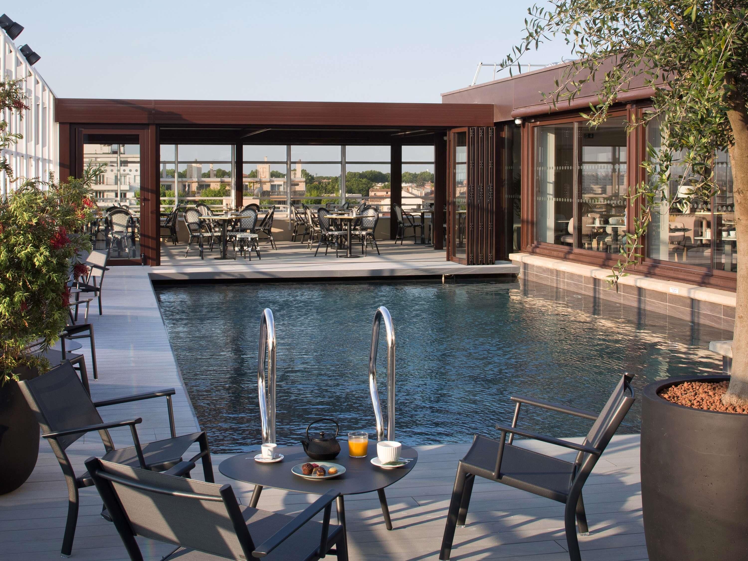 A rooftop pool area with outdoor seating and a view of the cityscape.