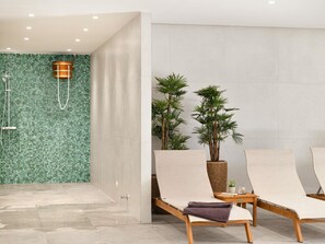 Relax in a serene spa area with a shower, lounge chairs, and lush greenery.