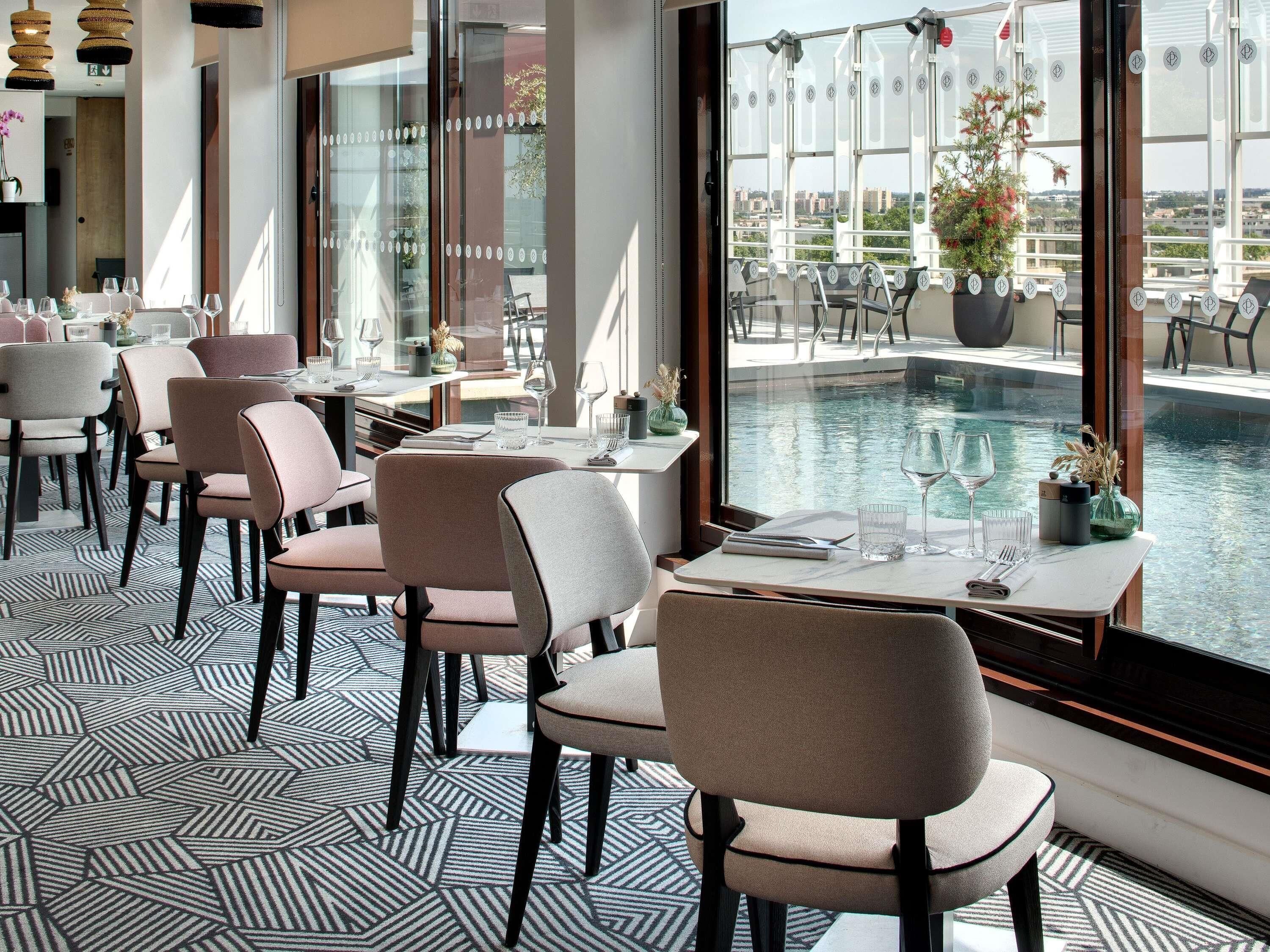 En restaurang med utsikt över poolen, moderna stolar och ett geometriskt mönster på golvet.