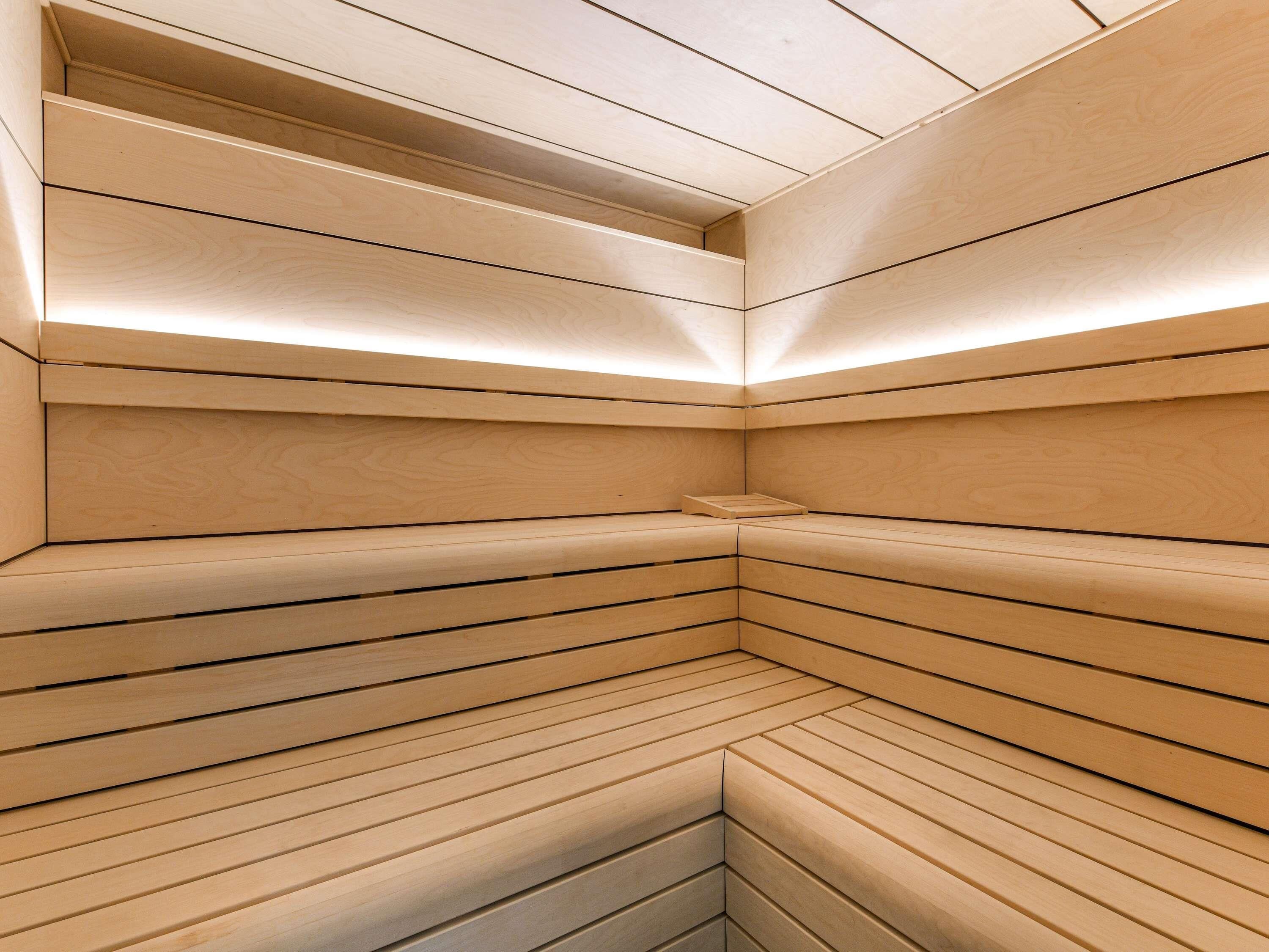 A modern, minimalist wooden sauna with slatted walls and a bench.