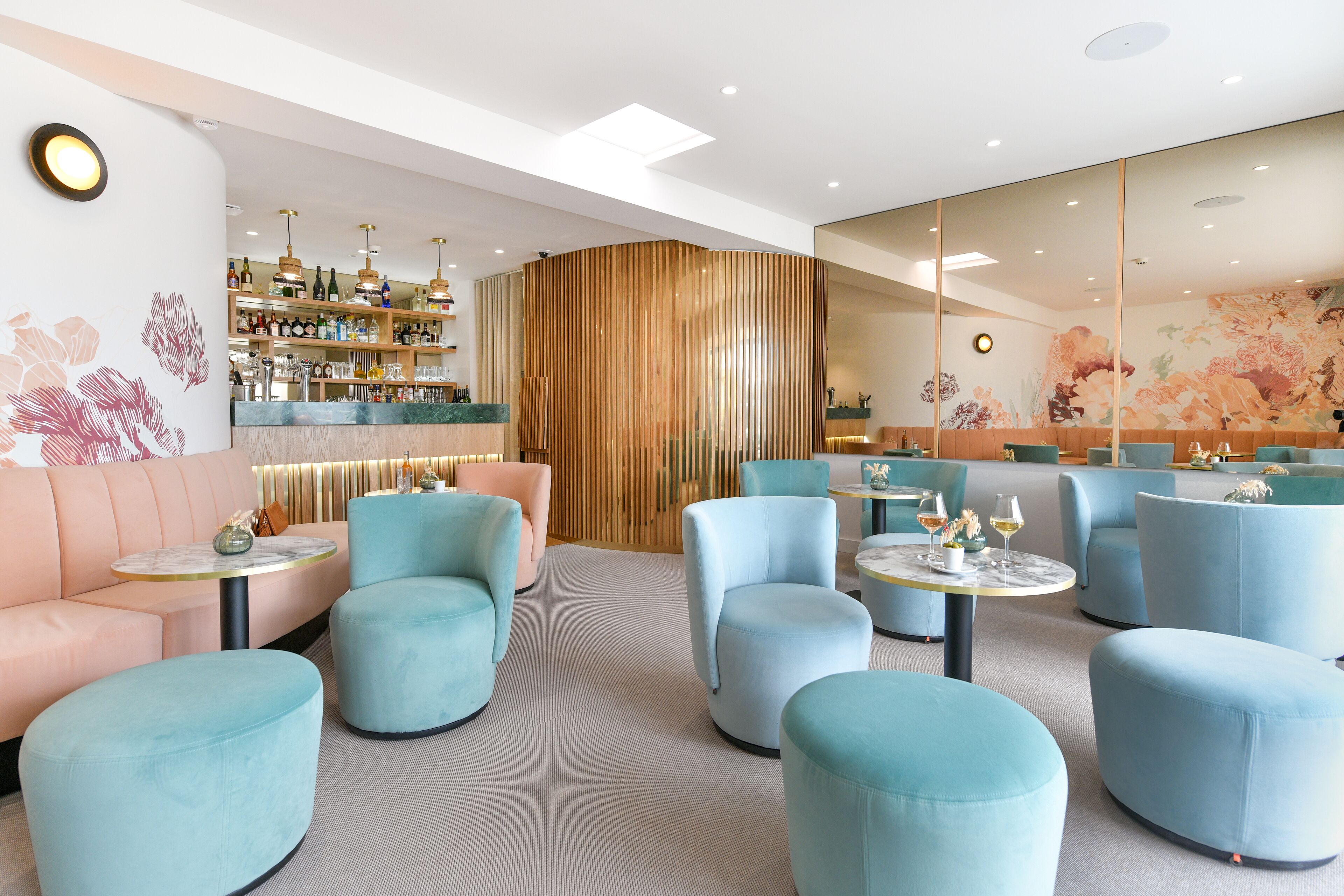 A modern lounge area with plush seating, a bar, and a decorative wall.