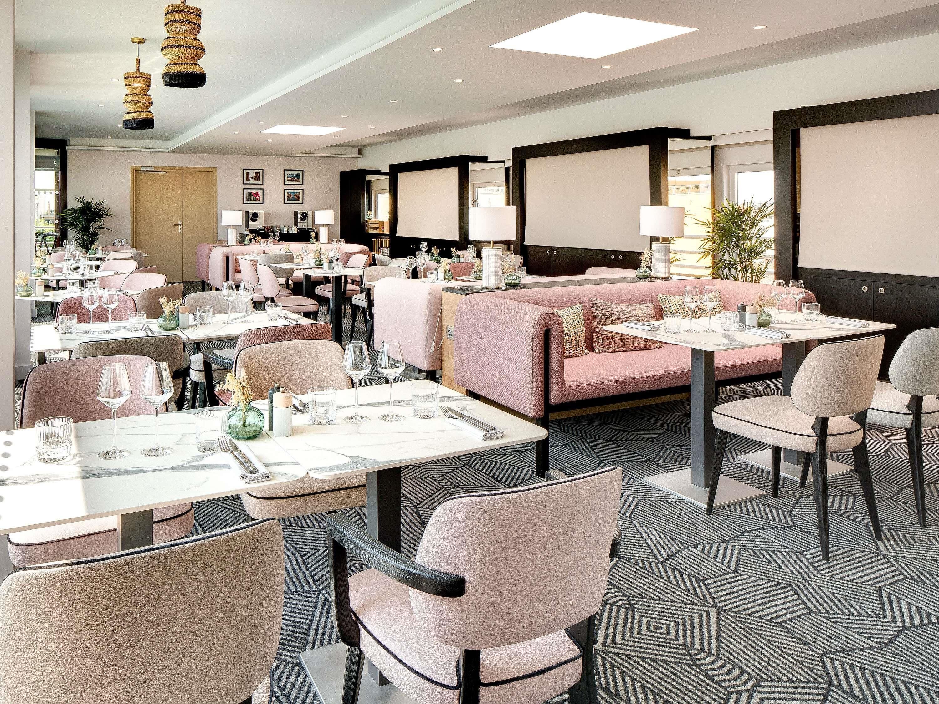 A modern dining area with tables set for meals, cushioned seating, and pendant lighting.