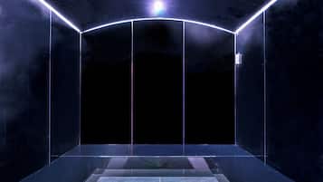 A dark, enclosed room with a reflective floor and walls, illuminated by a central light source.