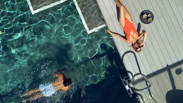 Una piscina con agua cristalina, un área de terraza y una mesa junto a la piscina con aperitivos.