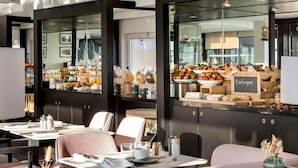 A modern dining area with a breakfast buffet, seating arrangements, and a view of the kitchen.