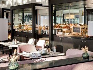 A modern dining area with a breakfast buffet, seating arrangements, and a view of the kitchen. - Pullman La Pléiade Montpellier Centre (Montpellier)