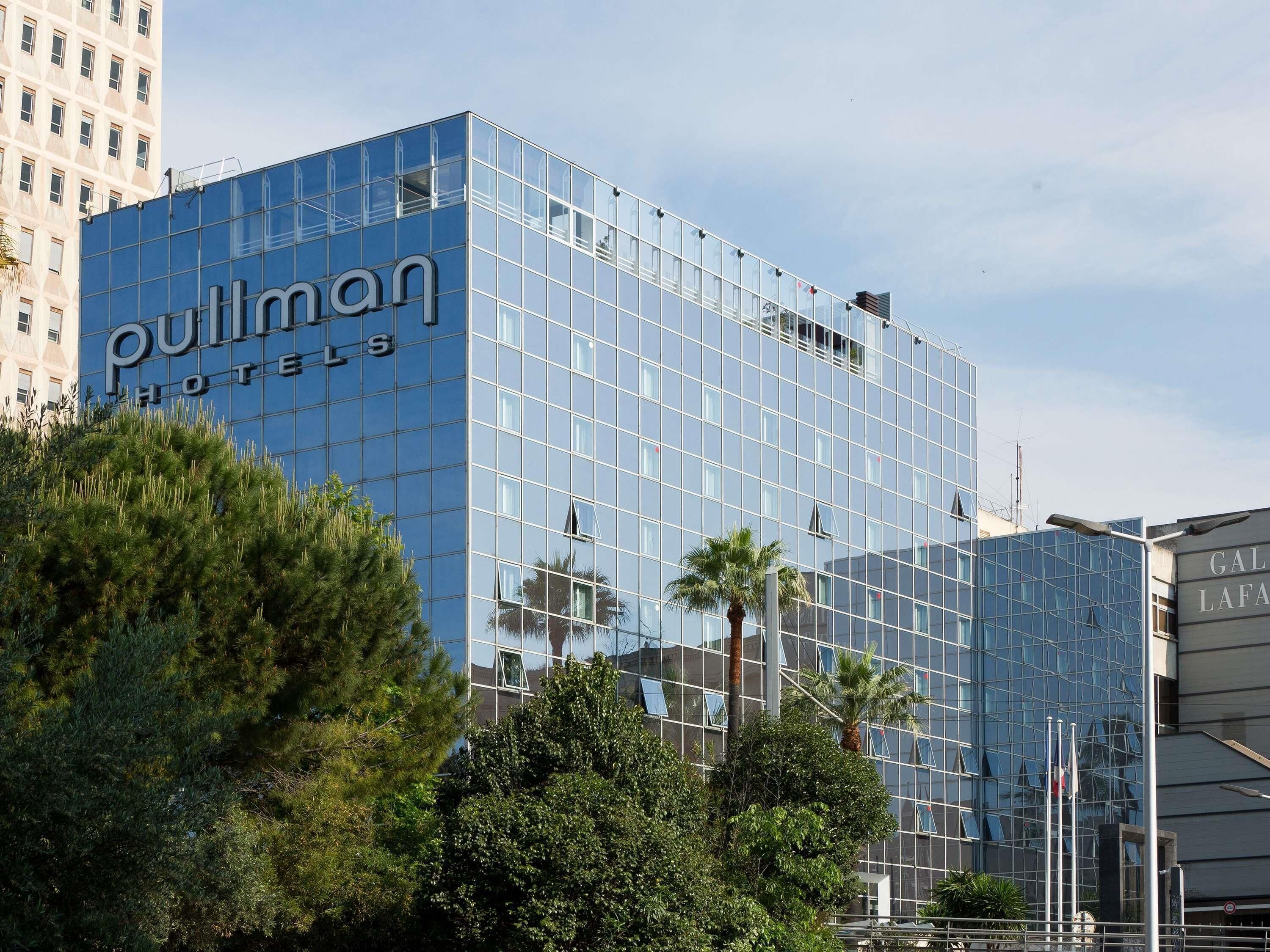 Ein modernes Hotelgebäude mit Glasfassade, auf der das Schriftzug 'Pullman Hotels' gut sichtbar angebracht ist.