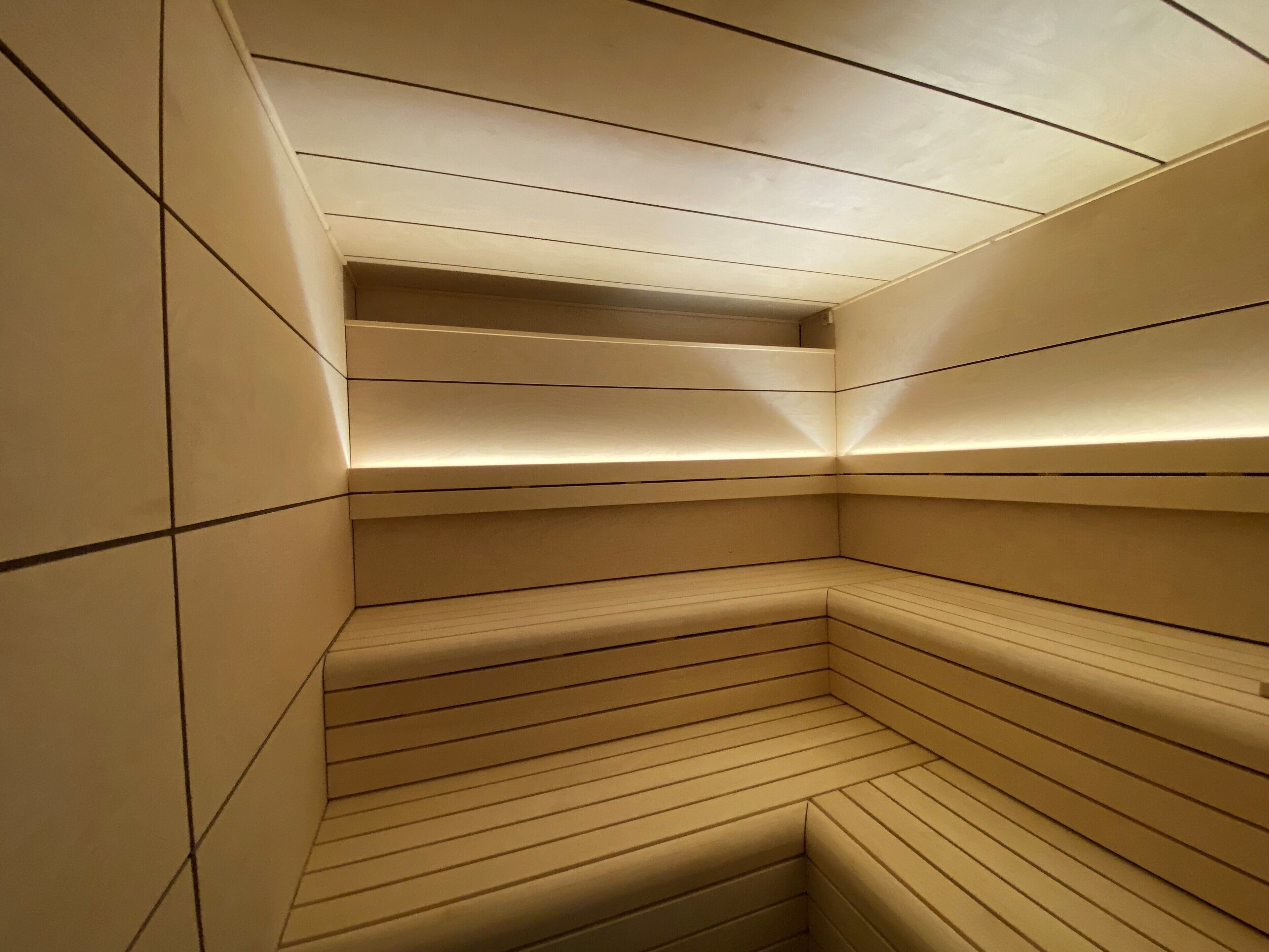 Un sauna moderne et minimaliste, doté d’un plafond incliné et de bancs intégrés.