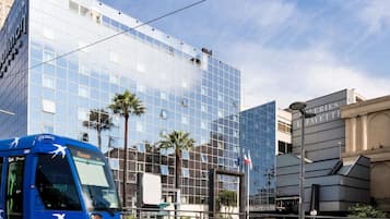 Een modern gebouw met een glazen gevel, een blauwe bus ervoor en een bordje met 'L'AFAYETTE' aan de rechterkant.
