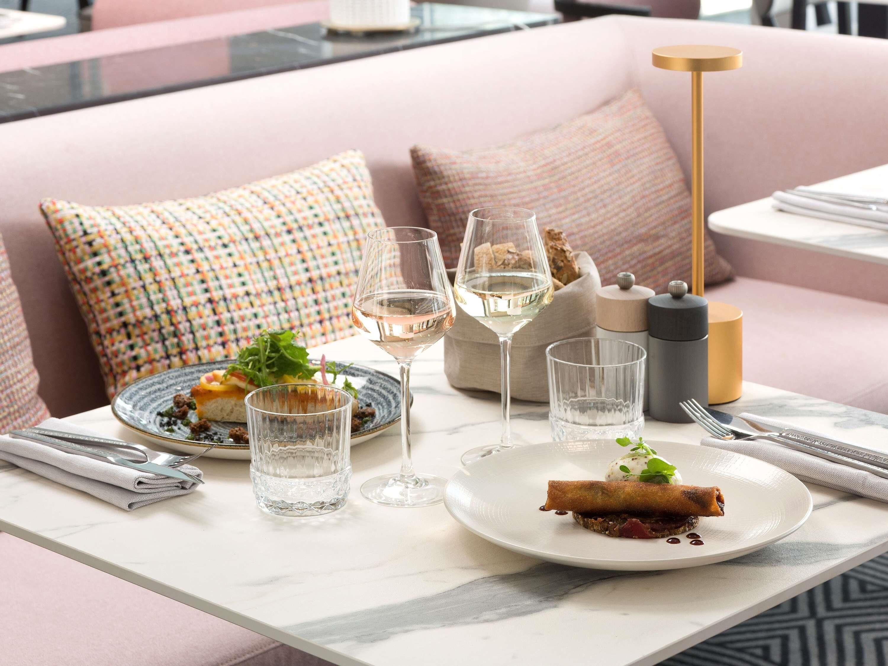 A dining table with plates of food, glasses of water and wine, and cutlery.