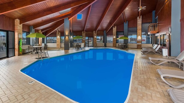 An indoor swimming pool with a wooden ceiling, lounge chairs, and tables. - Quality Inn Marysville (Marysville)