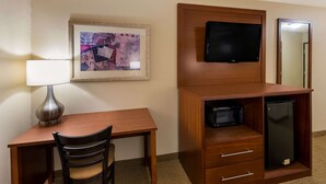A hotel room with a wooden desk, a chair, a television mounted on a wooden panel, a microwave, and a refrigerator. - Quality Inn Marysville (Marysville)