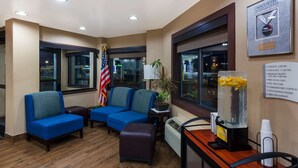 A hotel lobby with blue sofas, a flag, a clock, and a refreshment station. - Quality Inn Marysville (Marysville)