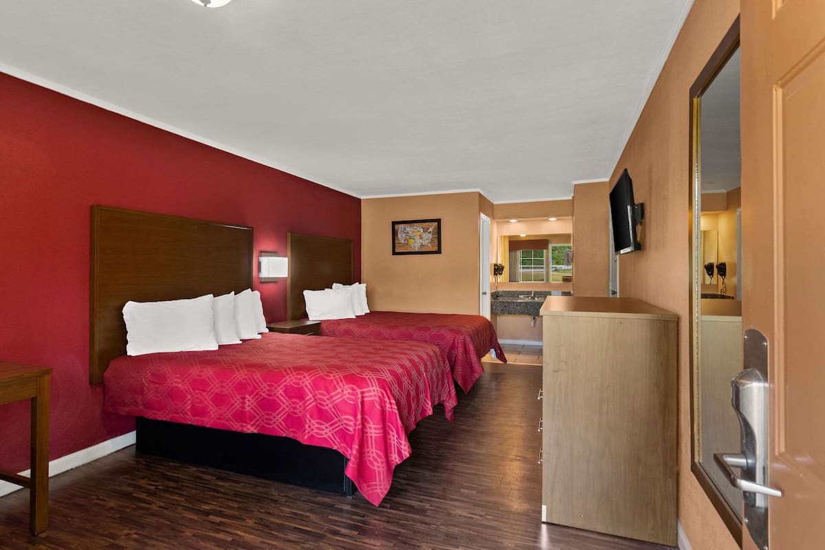A hotel room with a large bed, a desk, and a mirror.