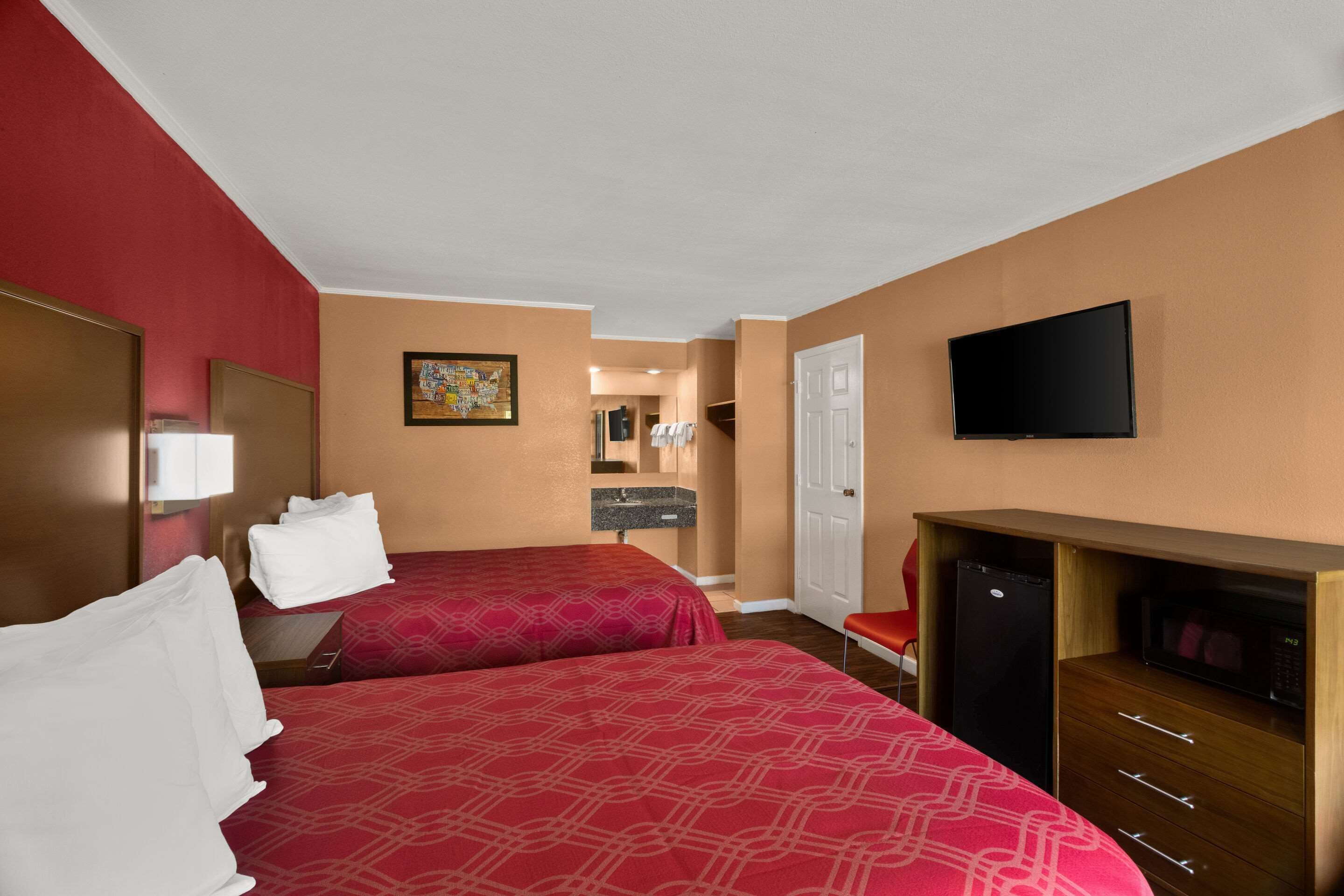 A hotel room with two beds, a TV, a microwave, and a refrigerator.