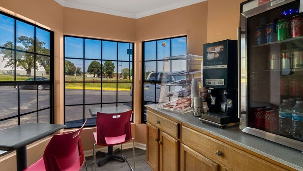 A coffee shop interior with large windows, a coffee machine, and a refrigerator stocked with beverages. - Econo Lodge Cornersville I-65 (Cornersville)