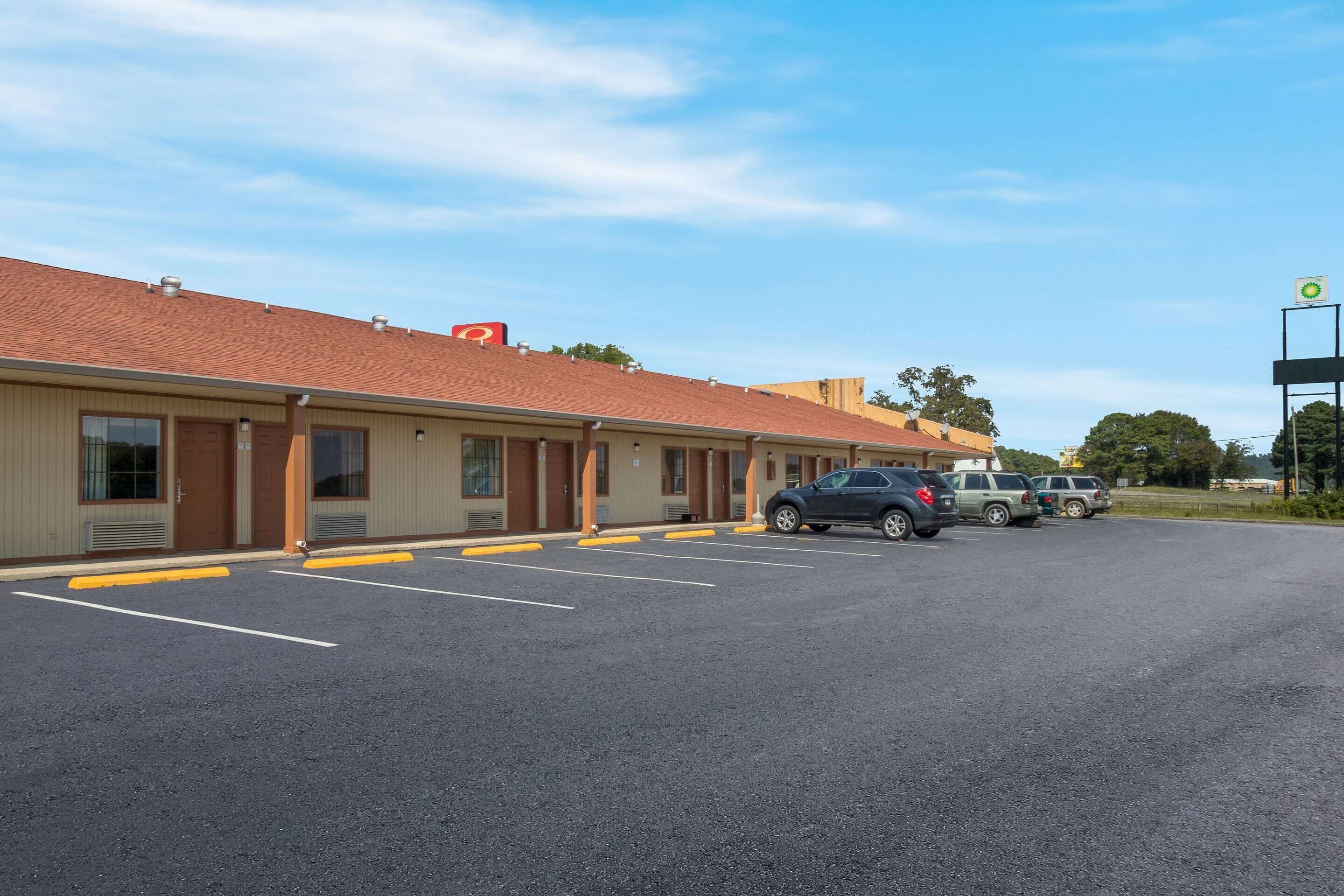 Un motel con estacionamiento, varios autos estacionados y un cielo despejado.