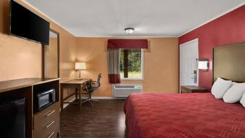 A hotel room with a bed, a desk, a chair, a television, and a window with curtains.