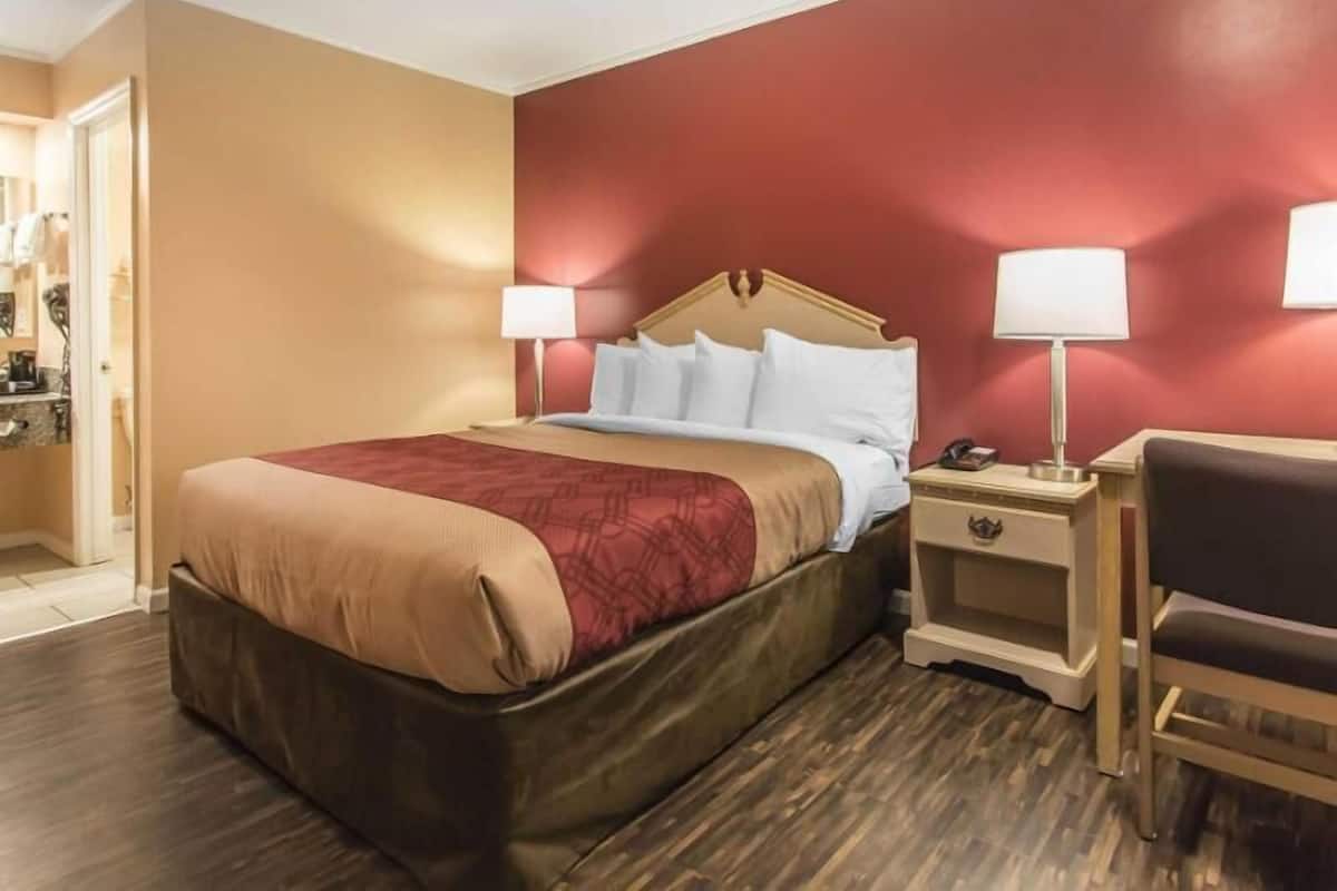 A hotel room with a bed, bedside tables, a chair, and a wardrobe.