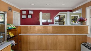 A reception area with a wooden counter, a refrigerator, and a display of snacks. - Econo Lodge Cornersville I-65 (Cornersville)