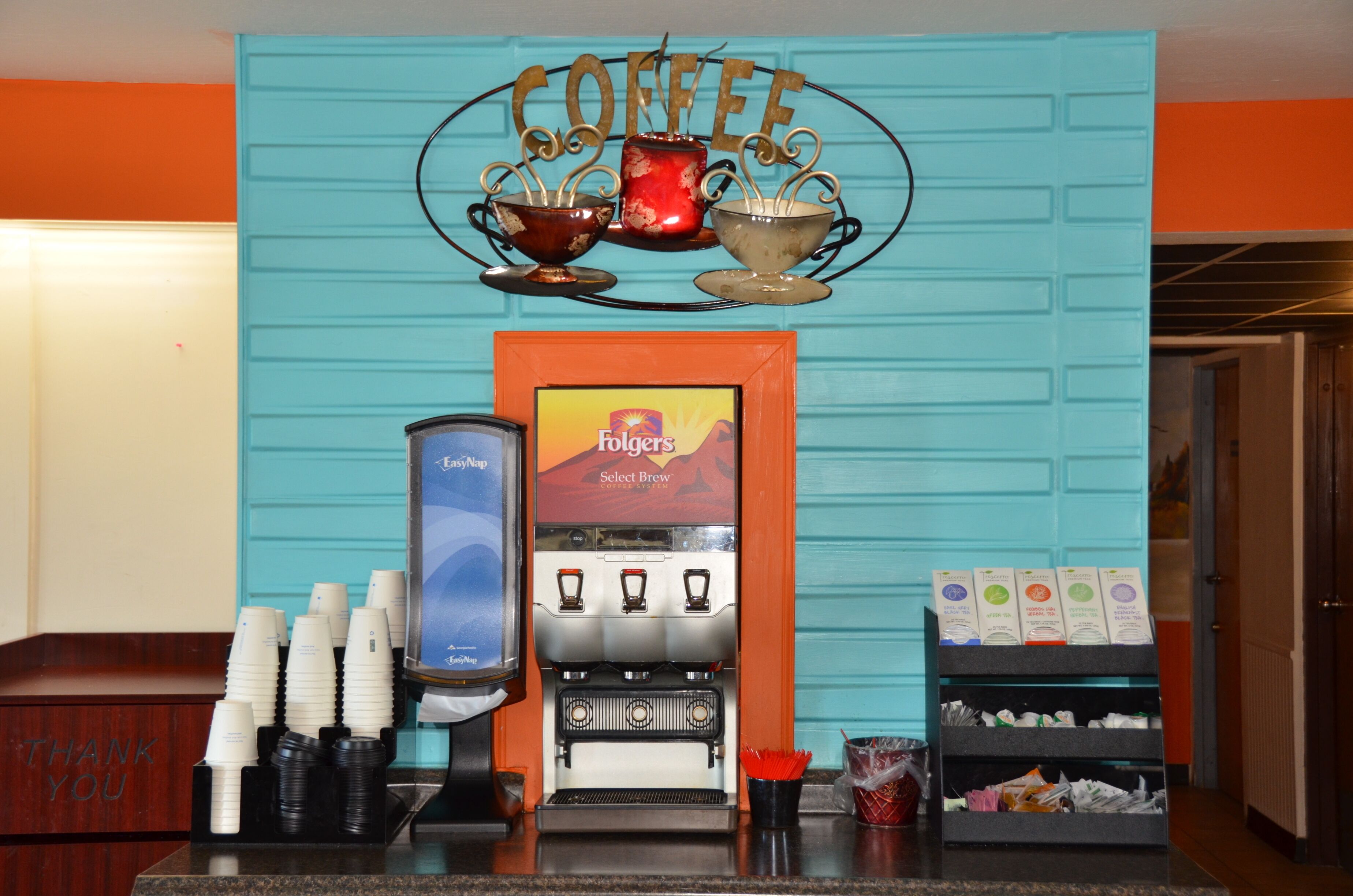 A coffee station with a coffee machine, cups, and a sign that reads "Coffee".