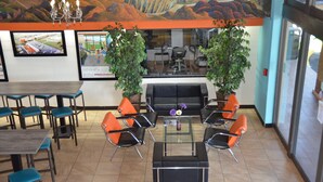Un restaurante con una decoración moderna, que ofrece una variedad de opciones de asientos, como mesas y sillas, una mesa de centro y plantas en macetas.
