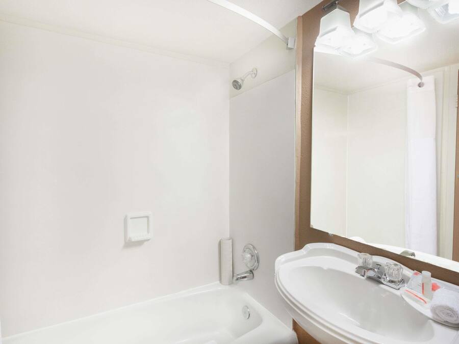 Une salle de bain avec un lavabo blanc, un miroir et une douche.