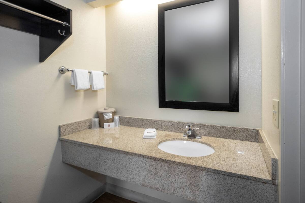 Un baño con lavamanos de encimera de granito, un espejo y un perchero para toallas.