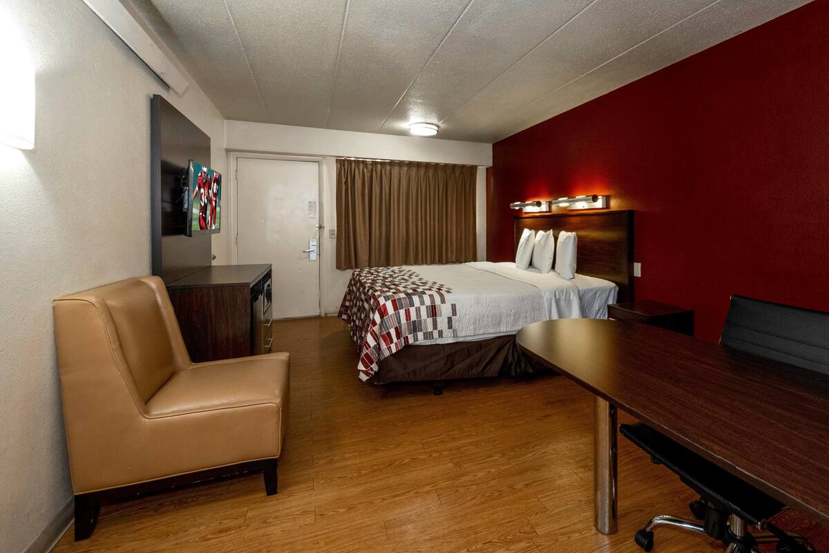 Una habitación de hotel con una cama, un escritorio, una silla y un televisor.