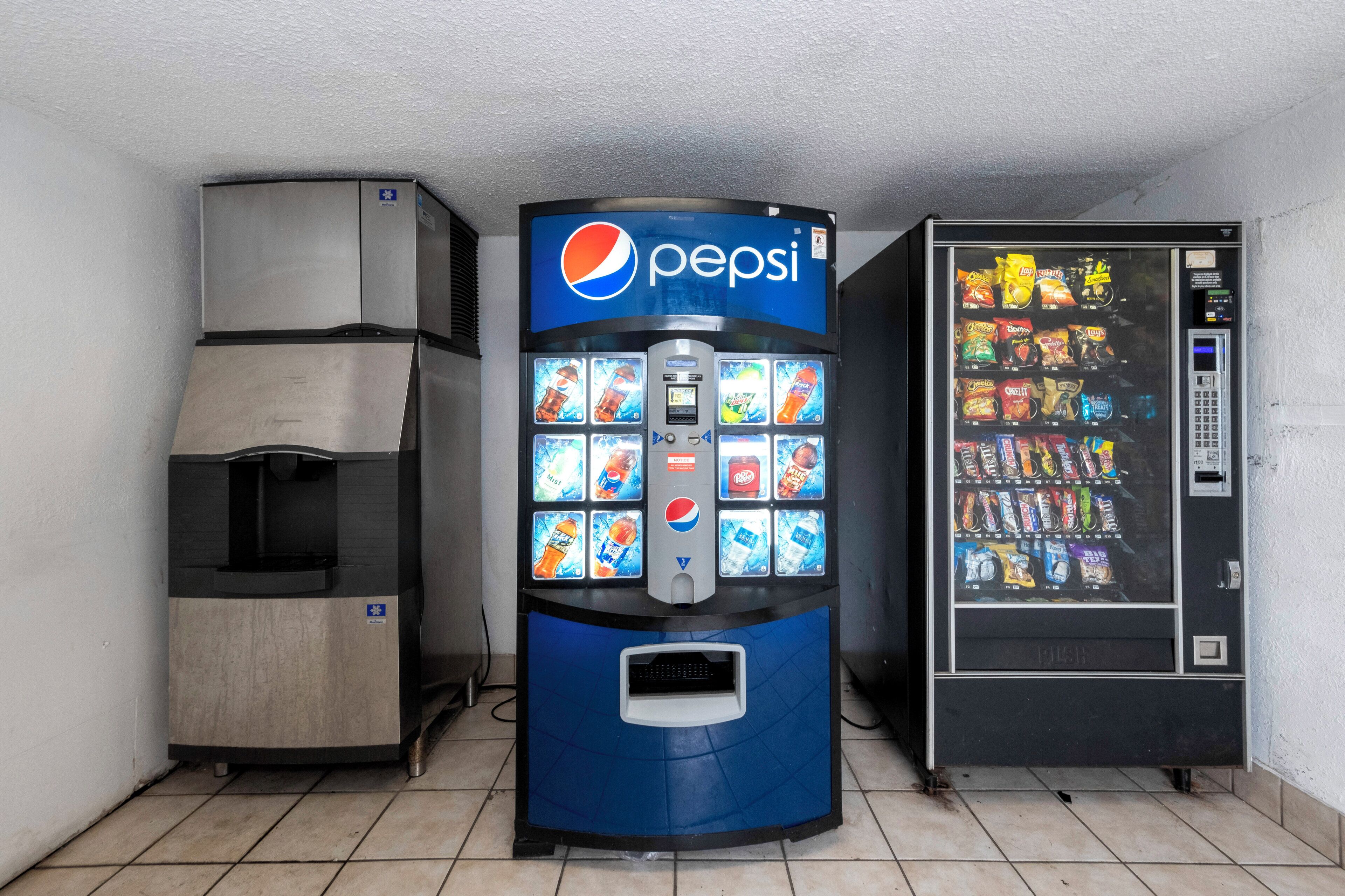 Máquina automática de bebidas com logomarca Pepsi, frigorífico e máquina de venda automática de snacks.