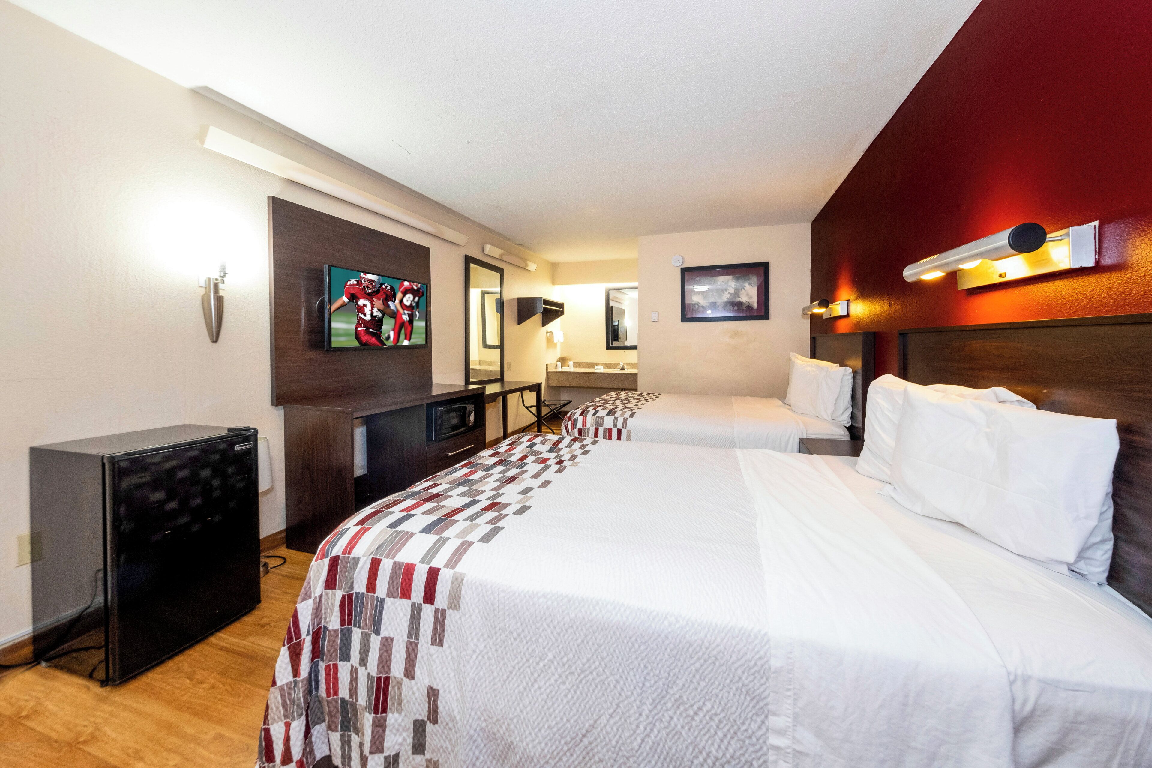 A hotel room with a large bed, a desk with a computer, a television, and a microwave.