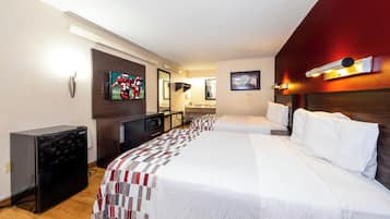 A hotel room with a large bed, a desk with a computer, a television, and a microwave.