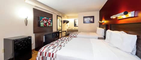 Una habitación de hotel con una cama grande, un escritorio con una computadora, un televisor y un microondas.