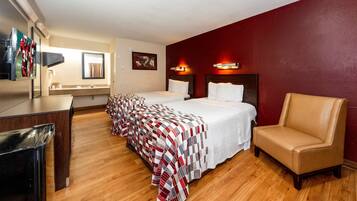 A hotel room with two beds, a desk, a chair, and a television.
