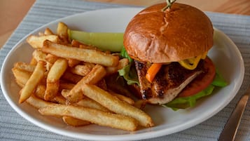 Un plato con una hamburguesa, papas fritas y un pepinillo.