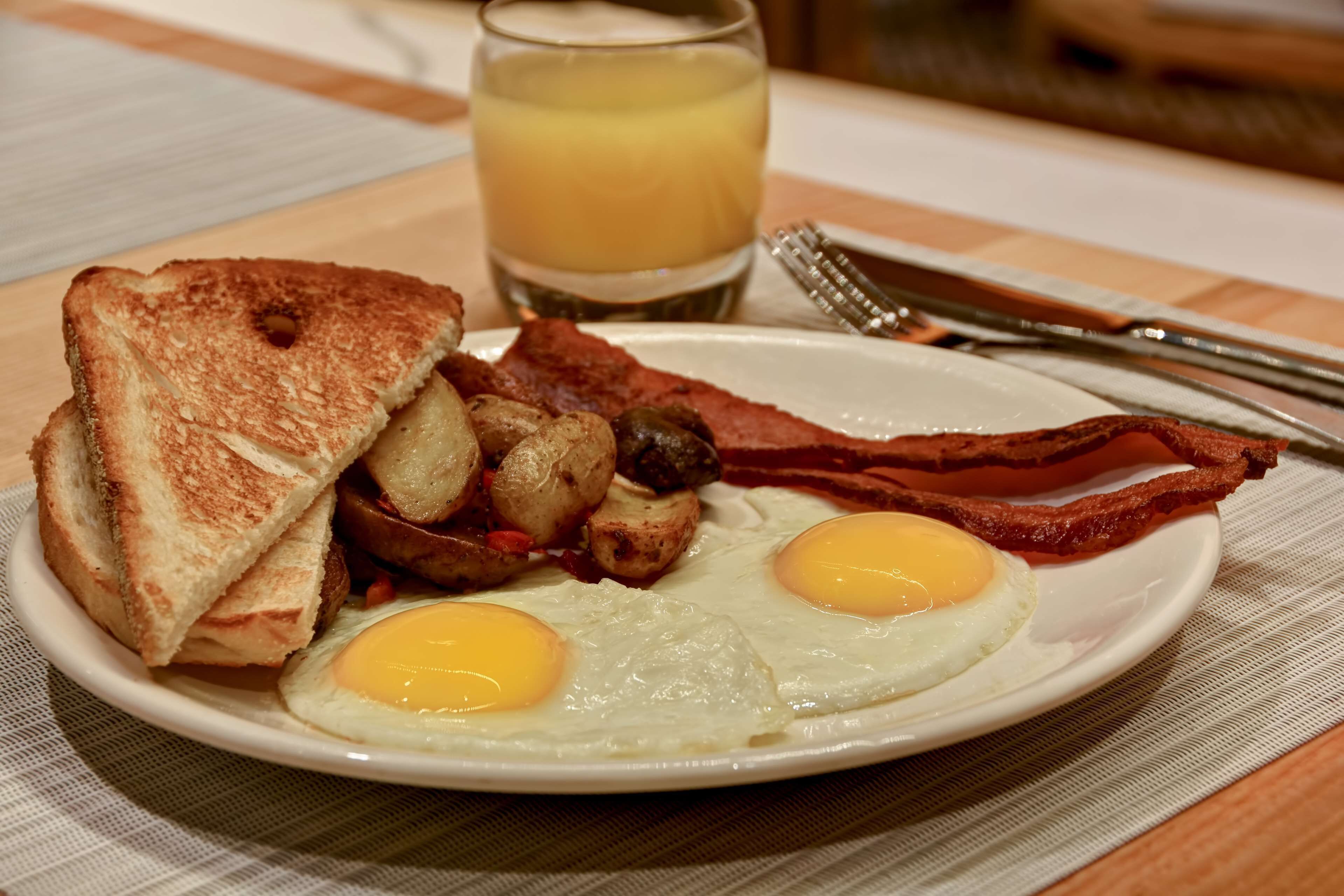 A plate of breakfast with toast, eggs, bacon, and potatoes.