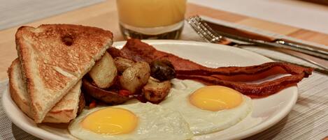 A plate of breakfast with toast, eggs, bacon, and potatoes.