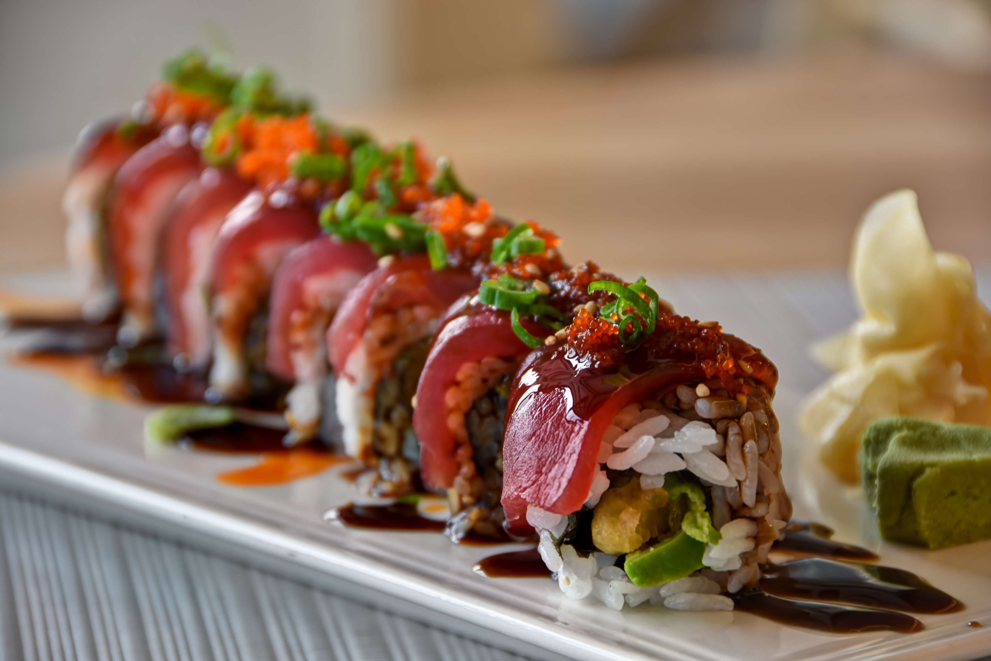 A sushi dish with rice, fish, and vegetables on a white plate.