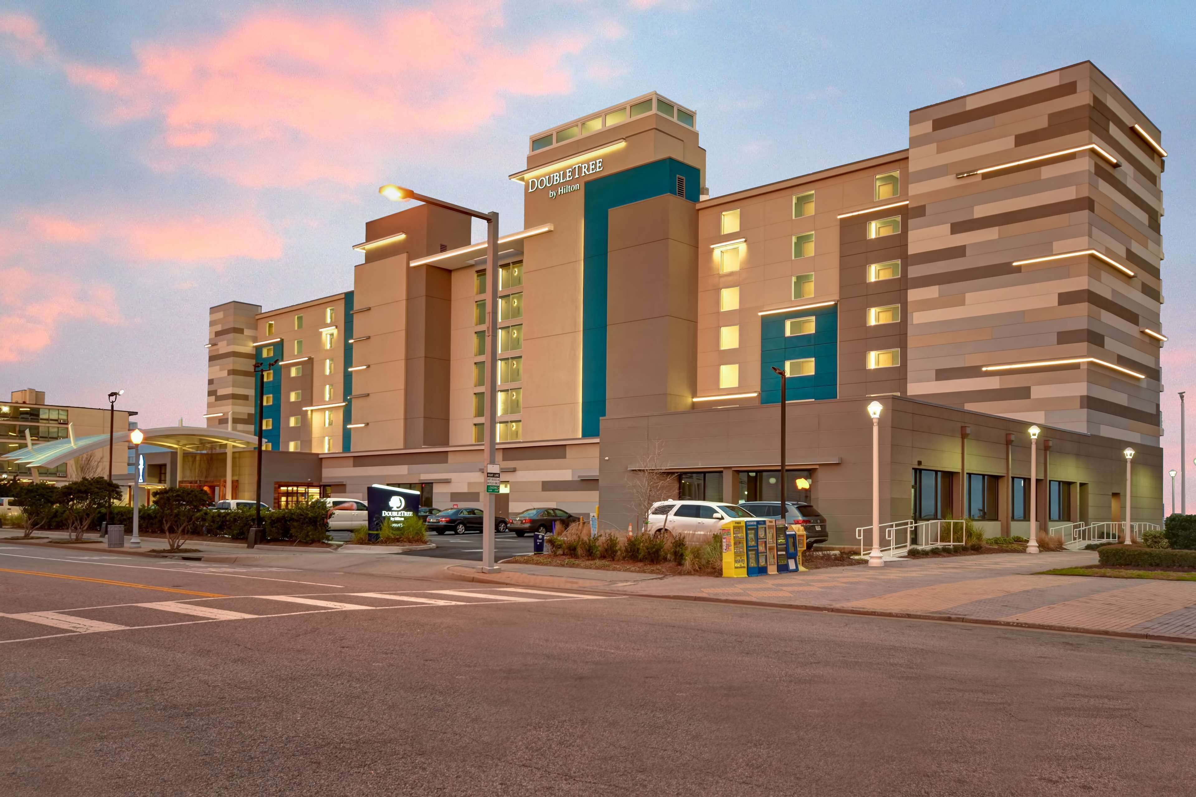 A modern hotel with a prominent 'DoubleTree by Hilton' sign, multiple floors, and a well-lit entrance area.