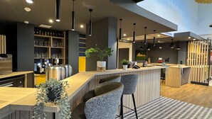 Eine moderne Bar mit Holztresen, Barhocker, Pendelleuchten und einem Schachbrettmuster auf dem Boden.
