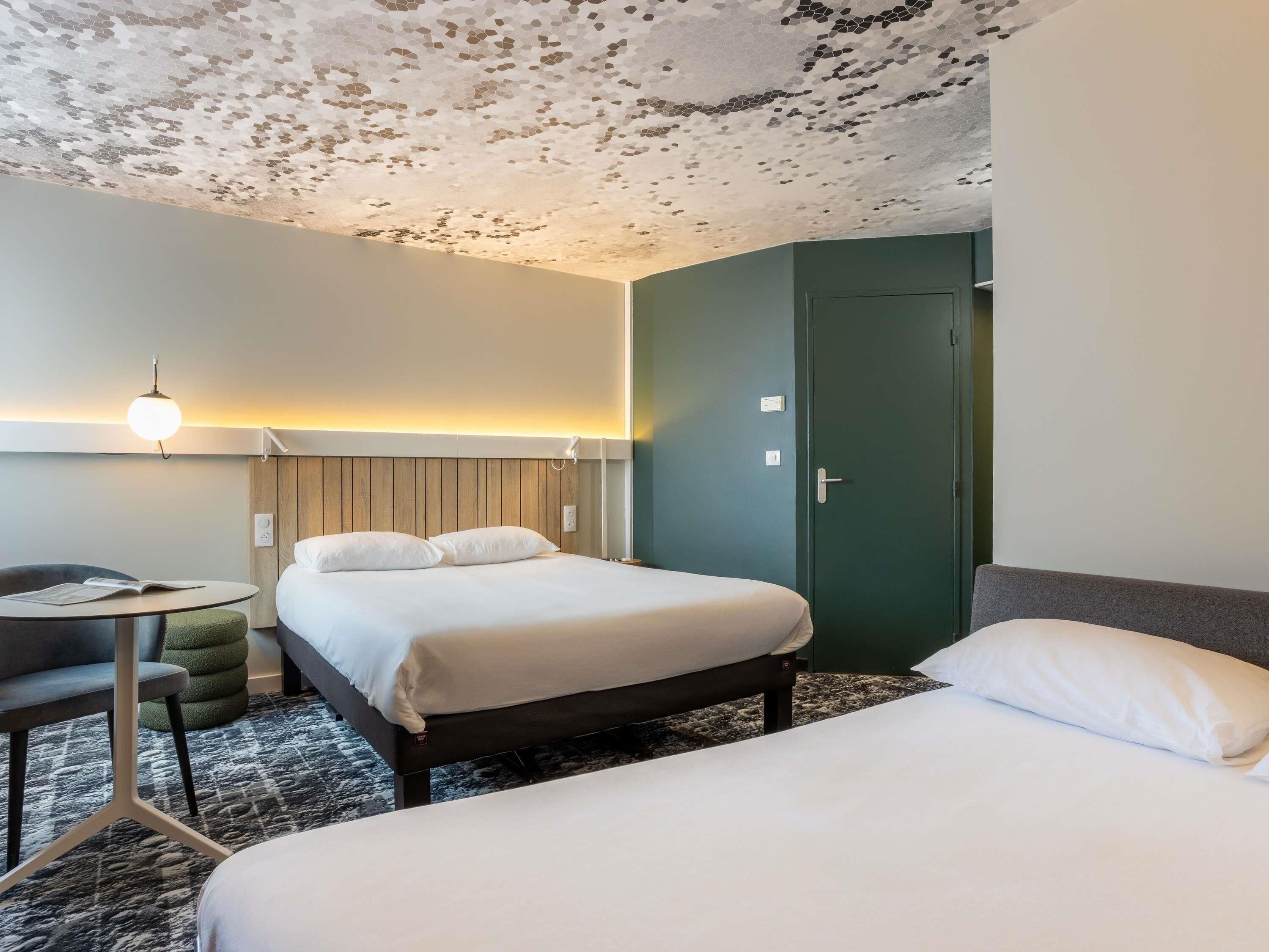 A hotel room with two beds, a desk, and a chair.
