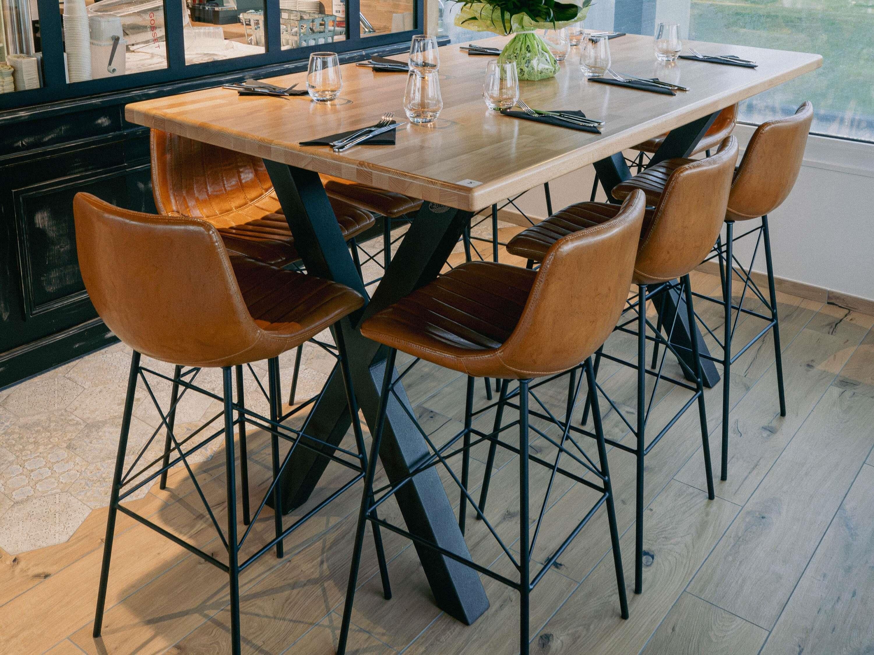 Un comedor con mesa de madera y sillas de cuero, un florero con flores, y una vista por la ventana.