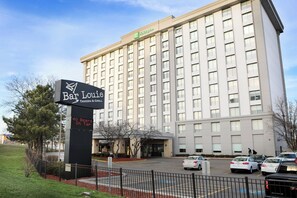 Un hotel con un cartel que dice 'Bar Louis Tavern & Grill' y una pantalla digital que indica '40 cervezas de barril'.