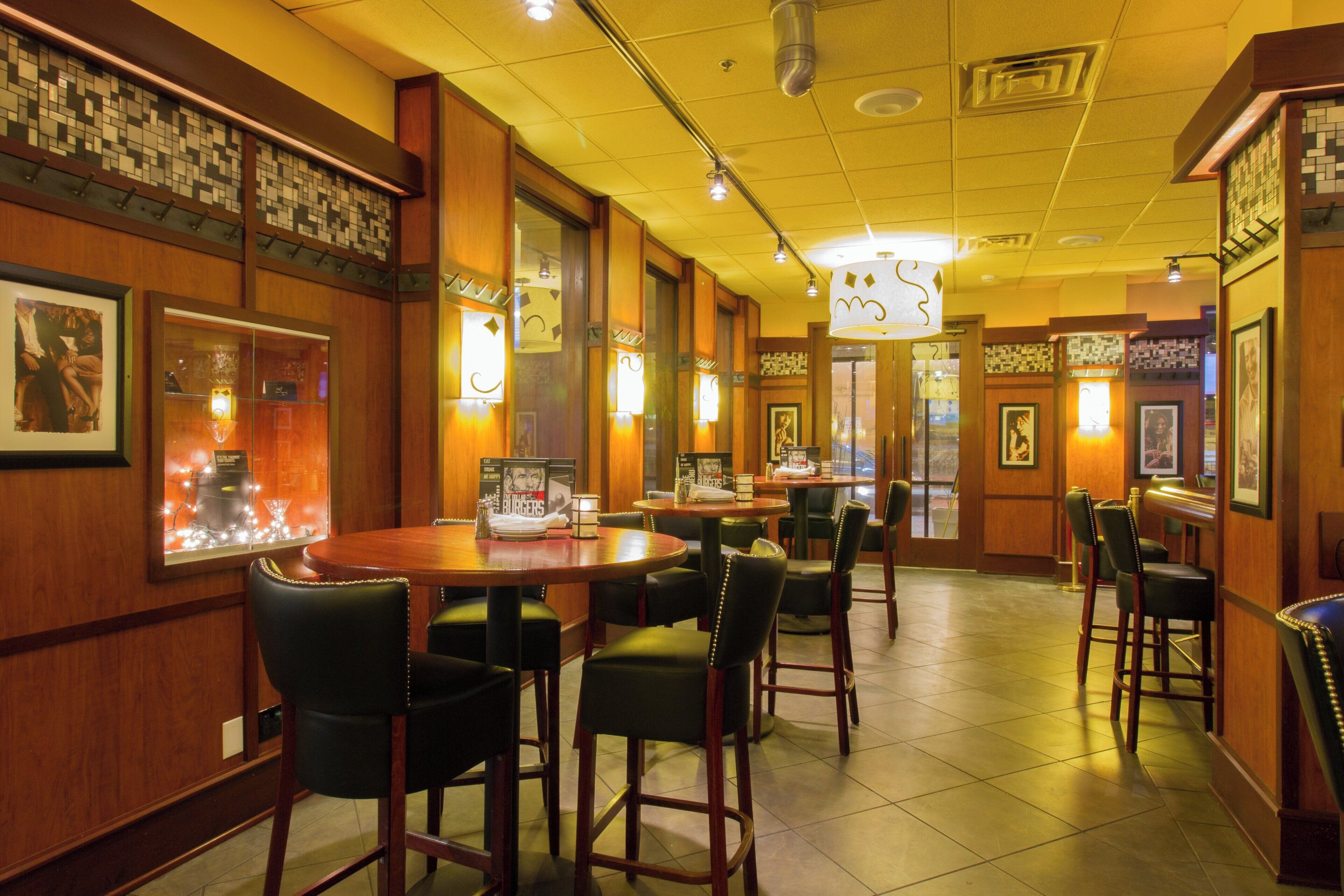 Un interior de restaurante con paneles de madera, varias mesas y sillas.