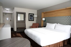A hotel room with a large bed, a desk, a chair, a mirror, and a door. - Holiday Inn Chicago O'Hare Area by IHG (Chicago)