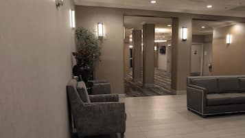 Vestíbulo de hotel con recepción, una planta y zona de estar.